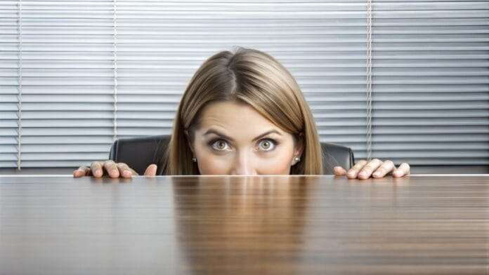Businesswoman Peeking Behind The Desk